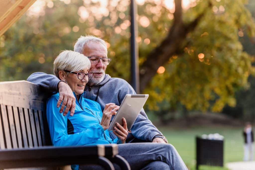 Elderly couple in park looking at iPad